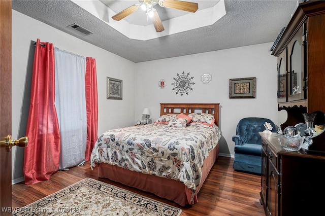 bedroom featuring a textured ceiling, ceiling fan, dark wood finished floors, and visible vents