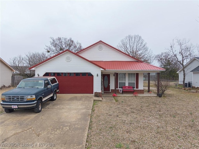 view of front of house with metal roof, an attached garage, covered porch, driveway, and a front yard