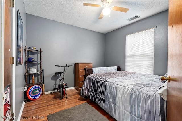 bedroom featuring a textured ceiling, dark wood-style flooring, visible vents, and baseboards