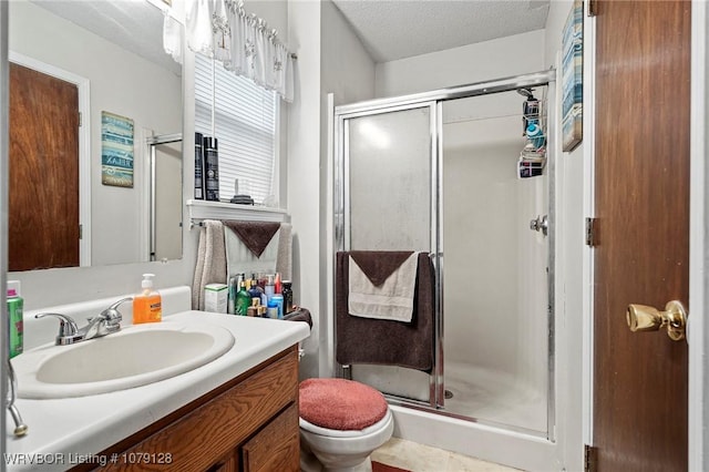 full bath with a textured ceiling, toilet, a stall shower, and vanity