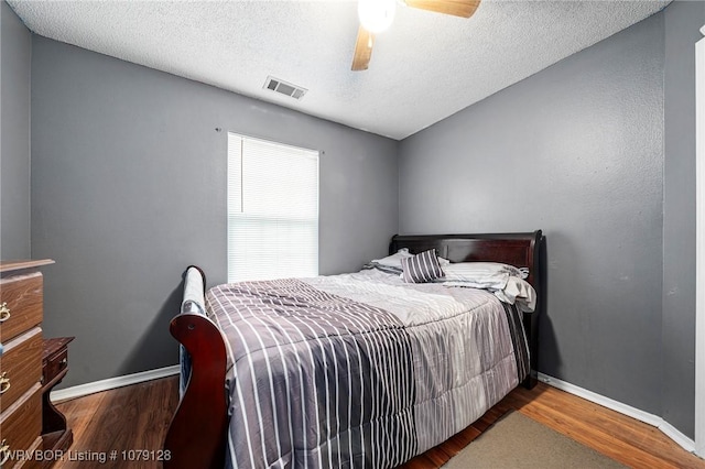 bedroom with ceiling fan, wood finished floors, visible vents, and baseboards