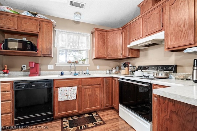 kitchen featuring black appliances, under cabinet range hood, light countertops, and a sink