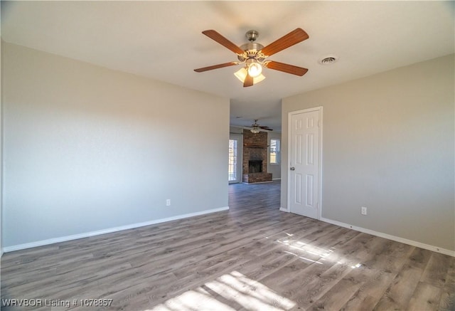 unfurnished room with hardwood / wood-style flooring, a fireplace, and ceiling fan