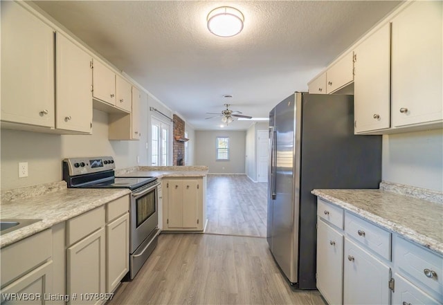 kitchen with ceiling fan, appliances with stainless steel finishes, white cabinets, a textured ceiling, and light wood-type flooring