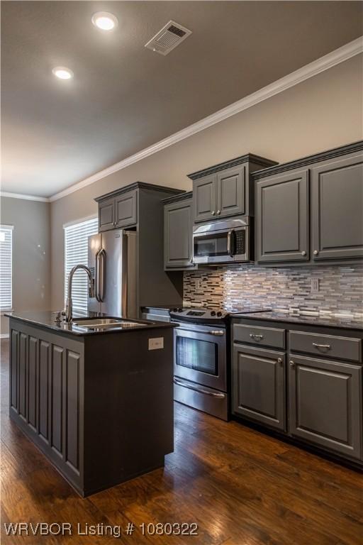 kitchen featuring stainless steel appliances, dark countertops, visible vents, gray cabinets, and crown molding