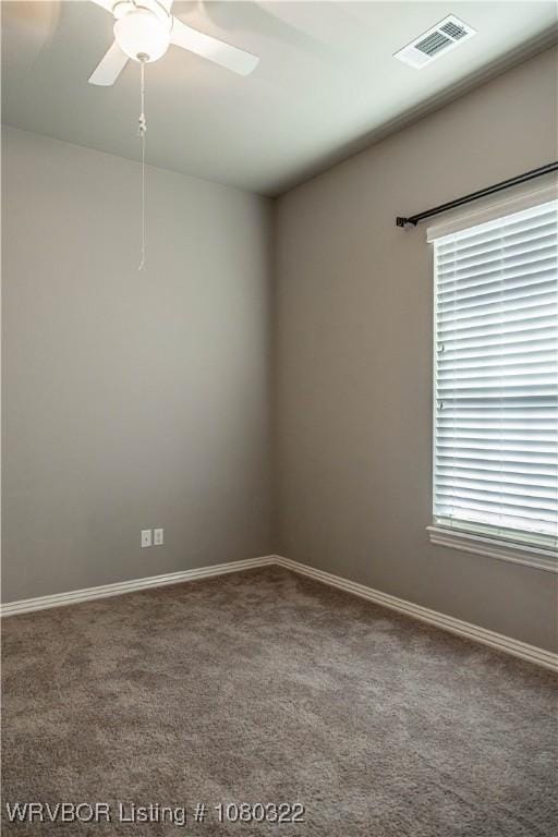 carpeted empty room featuring visible vents, a ceiling fan, and baseboards
