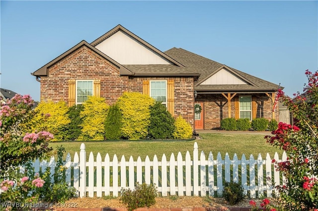 view of front of property featuring fence private yard, roof with shingles, a front yard, and brick siding
