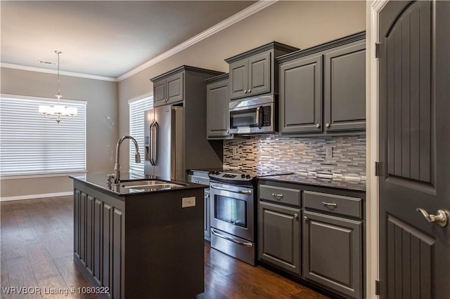 kitchen featuring stainless steel appliances, dark wood-type flooring, a center island with sink, decorative backsplash, and a chandelier