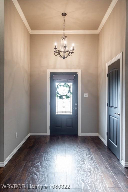 entryway with baseboards, wood finished floors, a chandelier, and crown molding