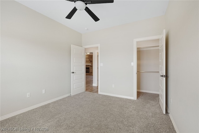 unfurnished bedroom featuring a walk in closet, ceiling fan, a closet, and light carpet