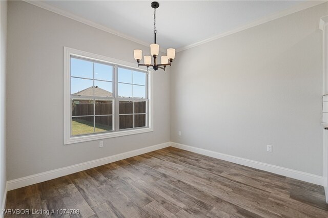 unfurnished room featuring hardwood / wood-style flooring, ornamental molding, and an inviting chandelier