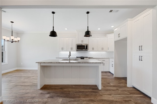 kitchen with a center island with sink, light stone countertops, white cabinetry, and sink