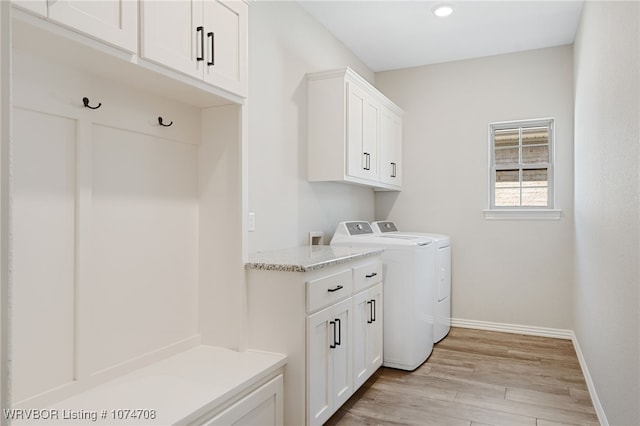 laundry area featuring cabinets, light wood-type flooring, and washing machine and clothes dryer