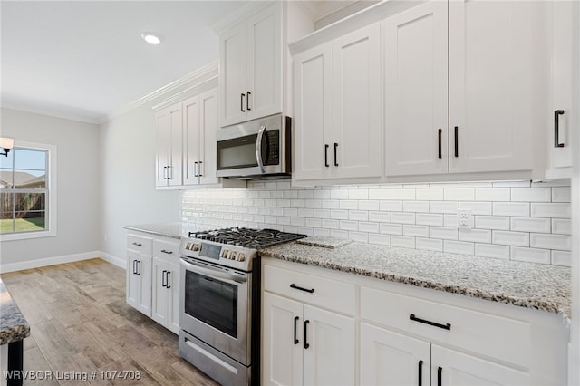 kitchen with decorative backsplash, light stone counters, ornamental molding, stainless steel appliances, and white cabinets