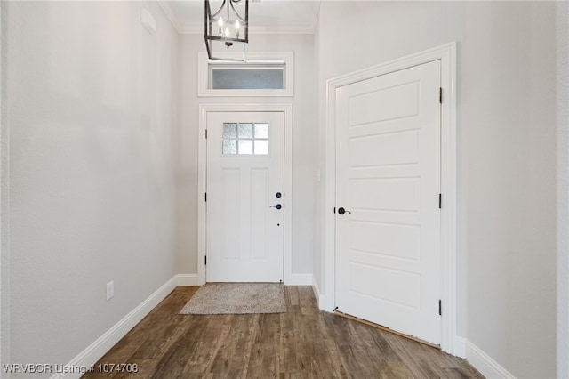 foyer entrance featuring hardwood / wood-style flooring, ornamental molding, and an inviting chandelier