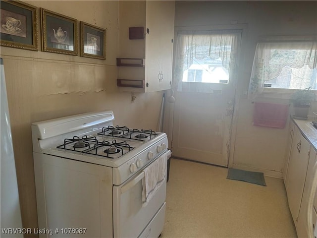 kitchen with white range with gas cooktop and white cabinets