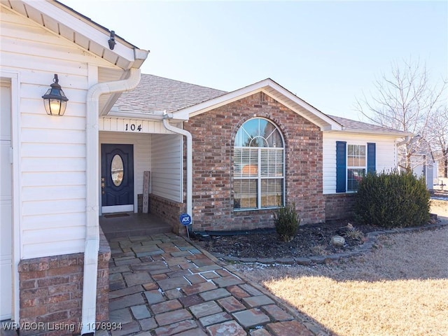 view of property exterior with a shingled roof, brick siding, and a garage