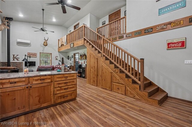 11667 Falling Rock Rd, Havana, AR 72842 - kitchen with ceiling fan, wood finished floors, an AC wall unit, brown cabinetry, and a high ceiling