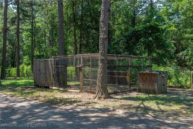 11667 Falling Rock Rd, Havana, AR 72842 - gate featuring a view of trees and a storage unit