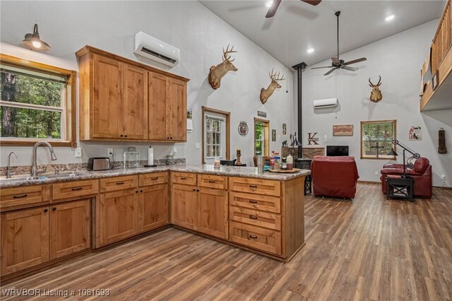 11667 Falling Rock Rd, Havana, AR 72842 - kitchen featuring a wall unit AC, wood finished floors, a ceiling fan, a peninsula, and healthy amount of natural light