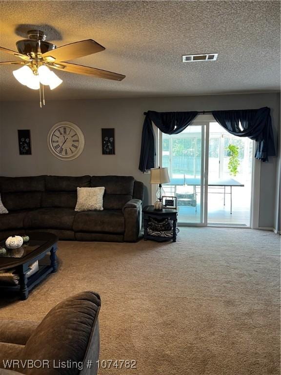 carpeted living room with ceiling fan and a textured ceiling