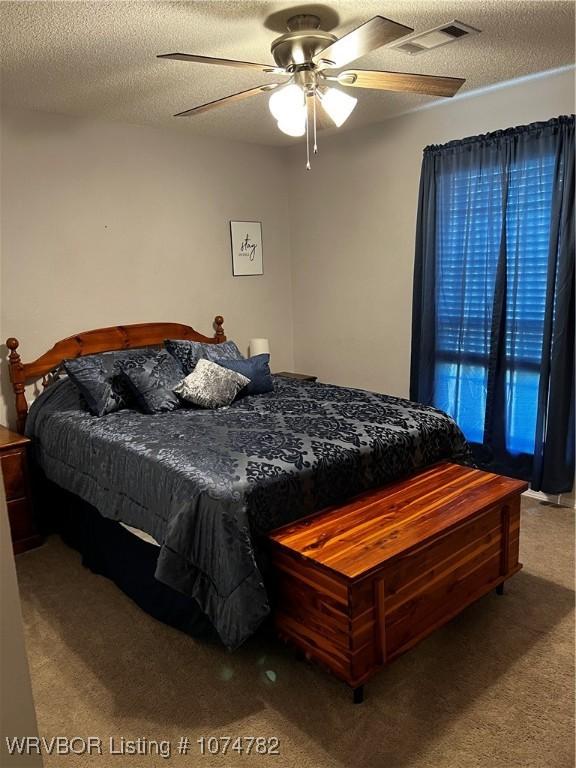 bedroom featuring carpet flooring, a textured ceiling, and ceiling fan