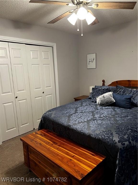 carpeted bedroom with a textured ceiling, a closet, and ceiling fan