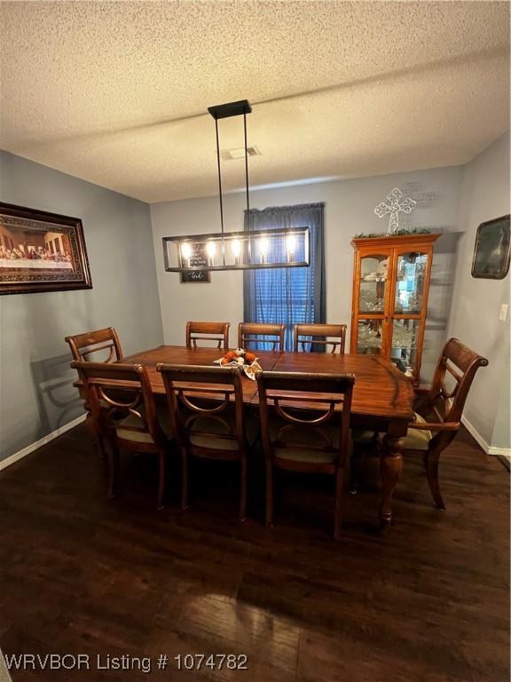 dining room featuring dark hardwood / wood-style flooring and a textured ceiling