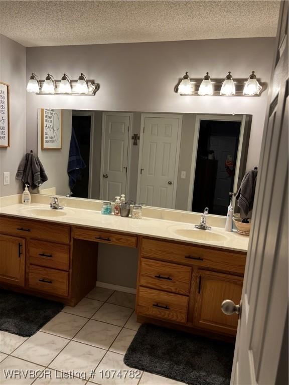 bathroom with tile patterned flooring, vanity, and a textured ceiling