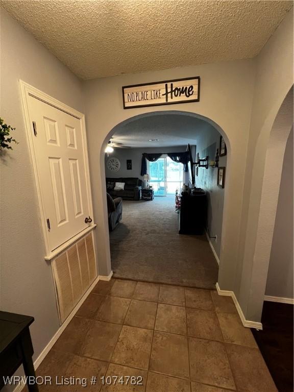 corridor featuring dark carpet and a textured ceiling