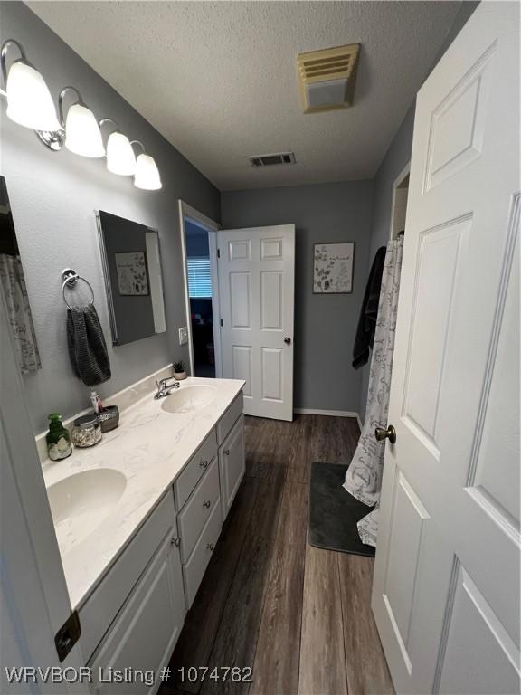 bathroom with hardwood / wood-style floors, vanity, and a textured ceiling