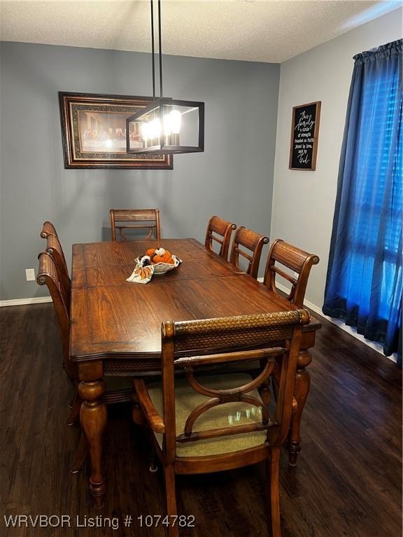 dining area featuring dark hardwood / wood-style flooring, a textured ceiling, and an inviting chandelier