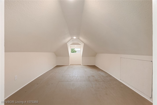 additional living space featuring a textured ceiling and vaulted ceiling