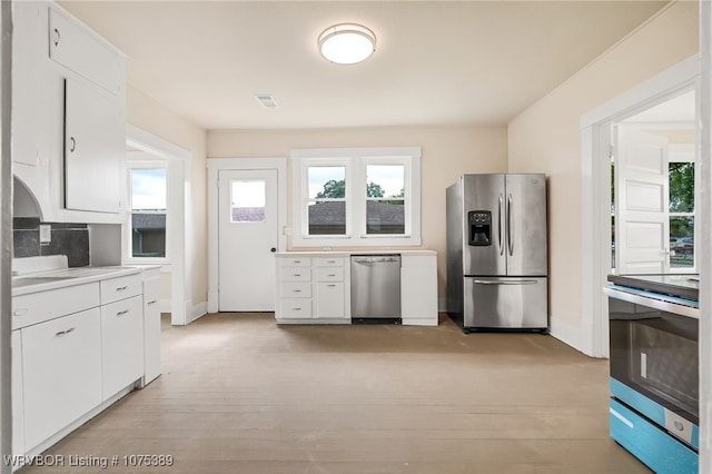 kitchen featuring tasteful backsplash, light hardwood / wood-style flooring, white cabinets, and stainless steel appliances