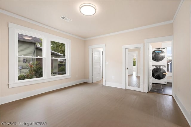 unfurnished bedroom with multiple windows, crown molding, and stacked washer and clothes dryer