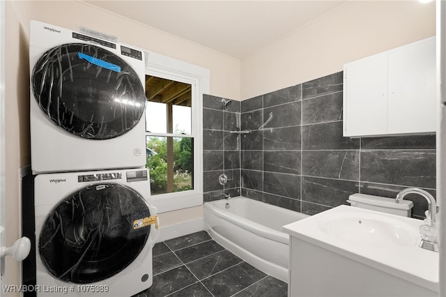 bathroom featuring a bathing tub, tile patterned floors, toilet, tile walls, and stacked washer / dryer