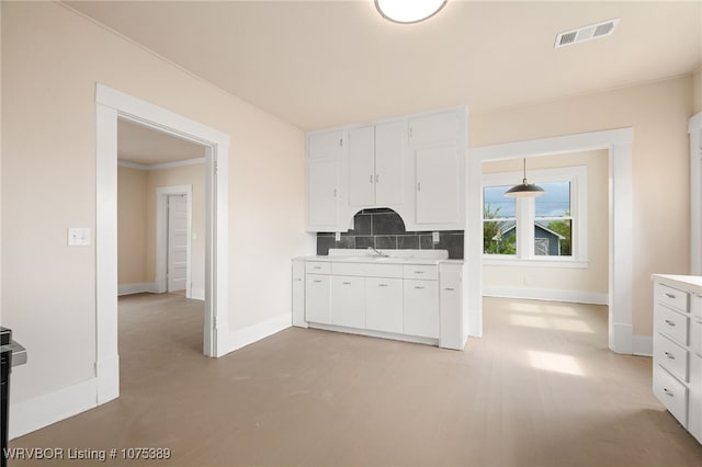 kitchen featuring tasteful backsplash, sink, white cabinets, and pendant lighting