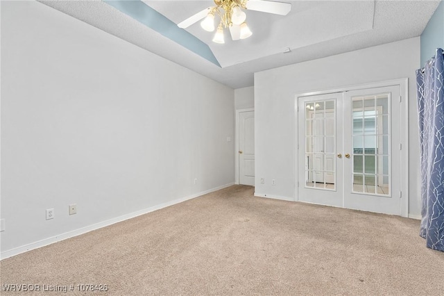 carpeted empty room featuring ceiling fan, french doors, and a tray ceiling