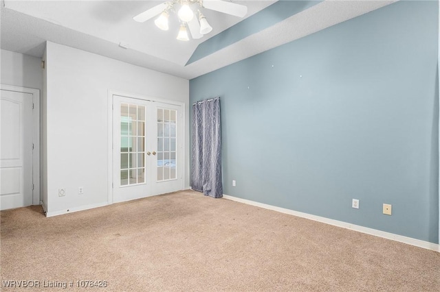 carpeted spare room with ceiling fan, lofted ceiling, and french doors