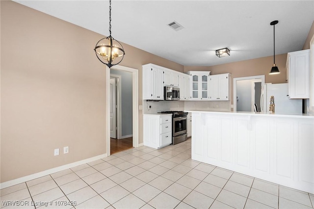 kitchen with hanging light fixtures, appliances with stainless steel finishes, an inviting chandelier, and white cabinetry