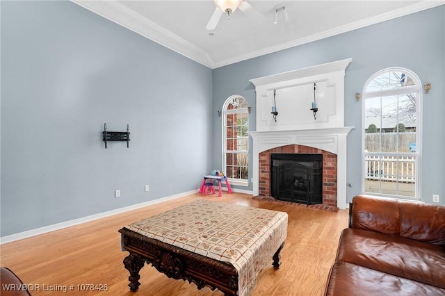 living room with ceiling fan, crown molding, a fireplace, and hardwood / wood-style floors