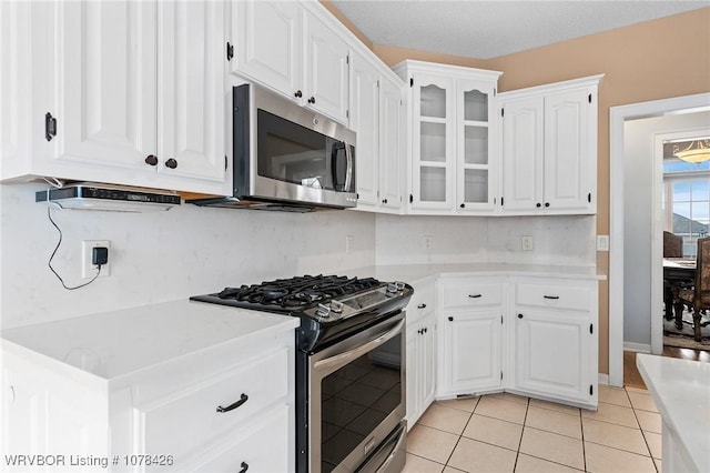 kitchen with white cabinets, appliances with stainless steel finishes, and light tile patterned floors