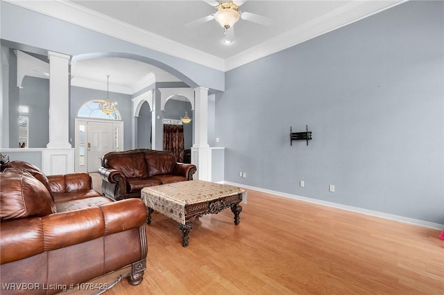 living room with decorative columns, light hardwood / wood-style floors, crown molding, and ceiling fan with notable chandelier