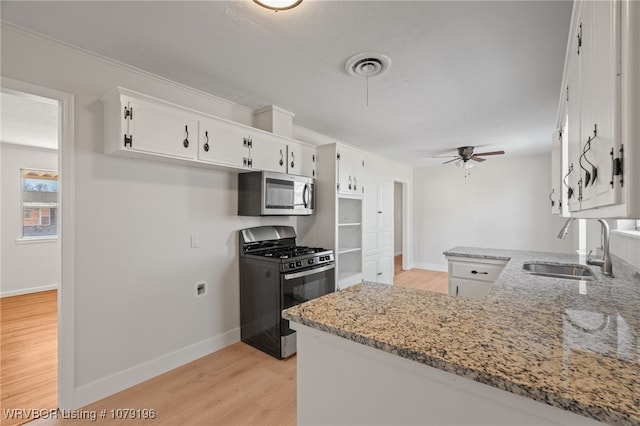 kitchen with black range with gas cooktop, white cabinets, stainless steel microwave, a peninsula, and a sink