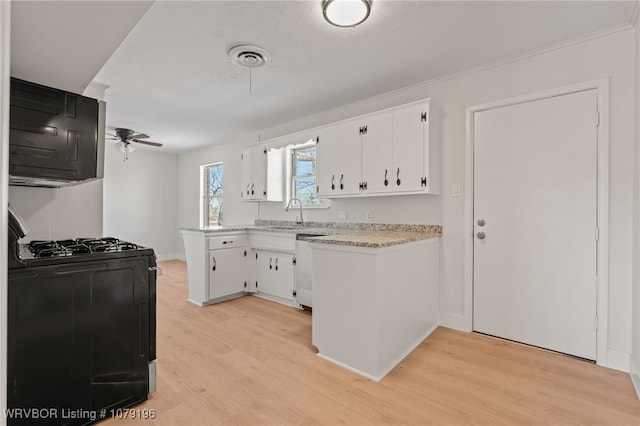 kitchen with light wood-style flooring, a peninsula, a sink, white cabinets, and black range with gas stovetop