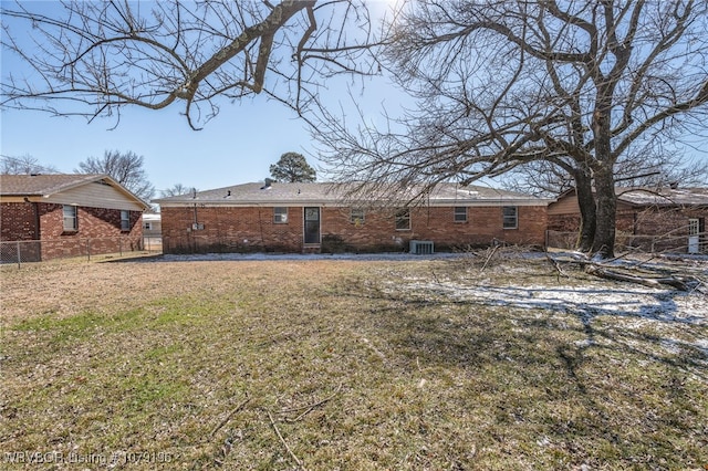 rear view of property featuring a yard, brick siding, fence, and central air condition unit