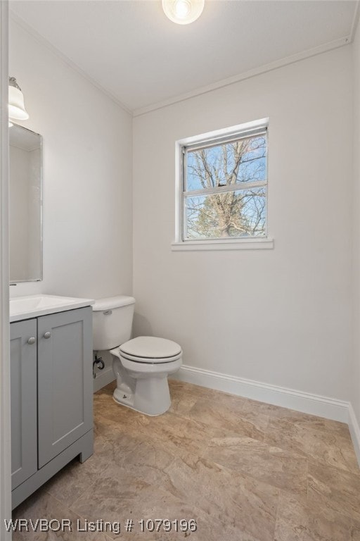 bathroom featuring toilet, baseboards, ornamental molding, and vanity