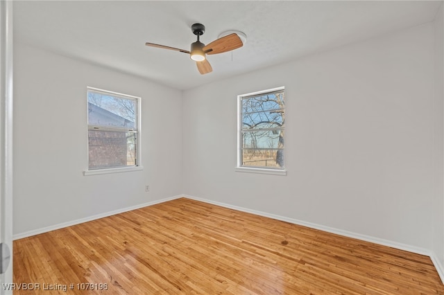 spare room with light wood-type flooring, a ceiling fan, and baseboards