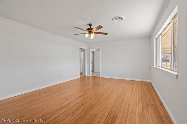 spare room featuring crown molding, visible vents, ceiling fan, light wood-type flooring, and baseboards