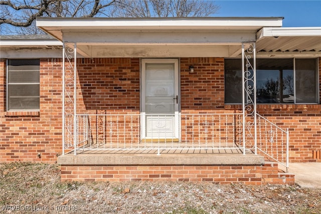 property entrance with covered porch and brick siding